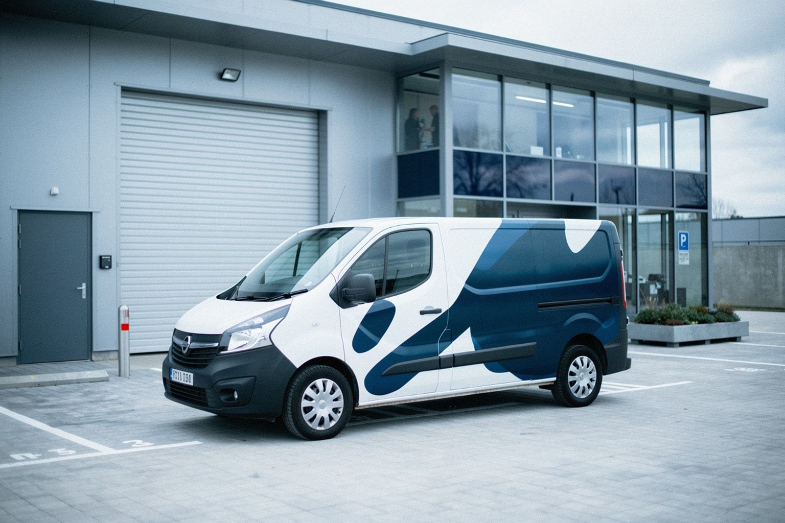 Beschrifteter weißer Werkstattwagen auf dem Hof eines Autohauses, dahinter Rolltor und Glasfront