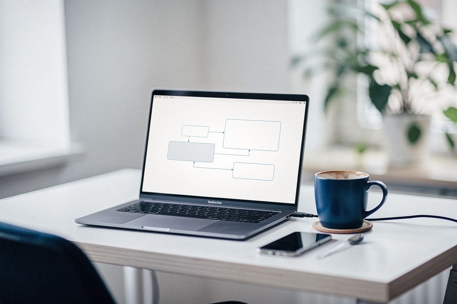 Laptop mit Workflow aus verbundenen Knoten, daneben Kaffee und Pflanze