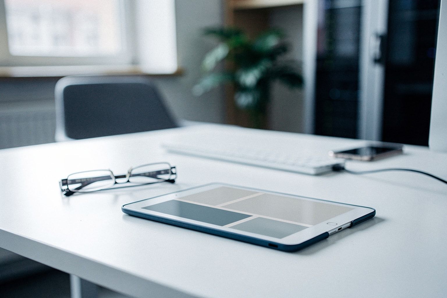 Tablet mit großen, kontrastreichen Bedienelementen, daneben eine Lesebrille