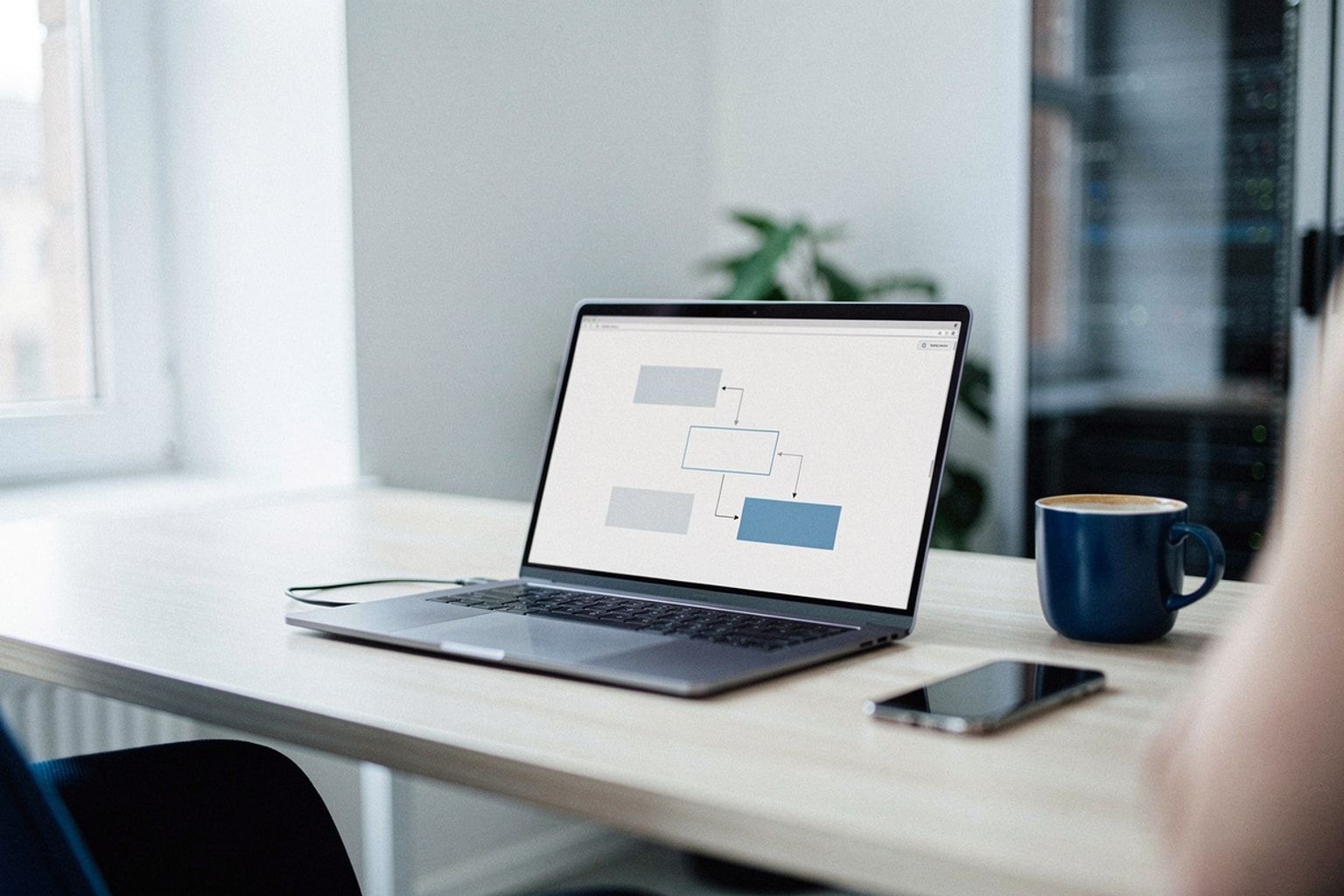 Laptop mit Workflow aus verbundenen Elementen, daneben ein Kaffee