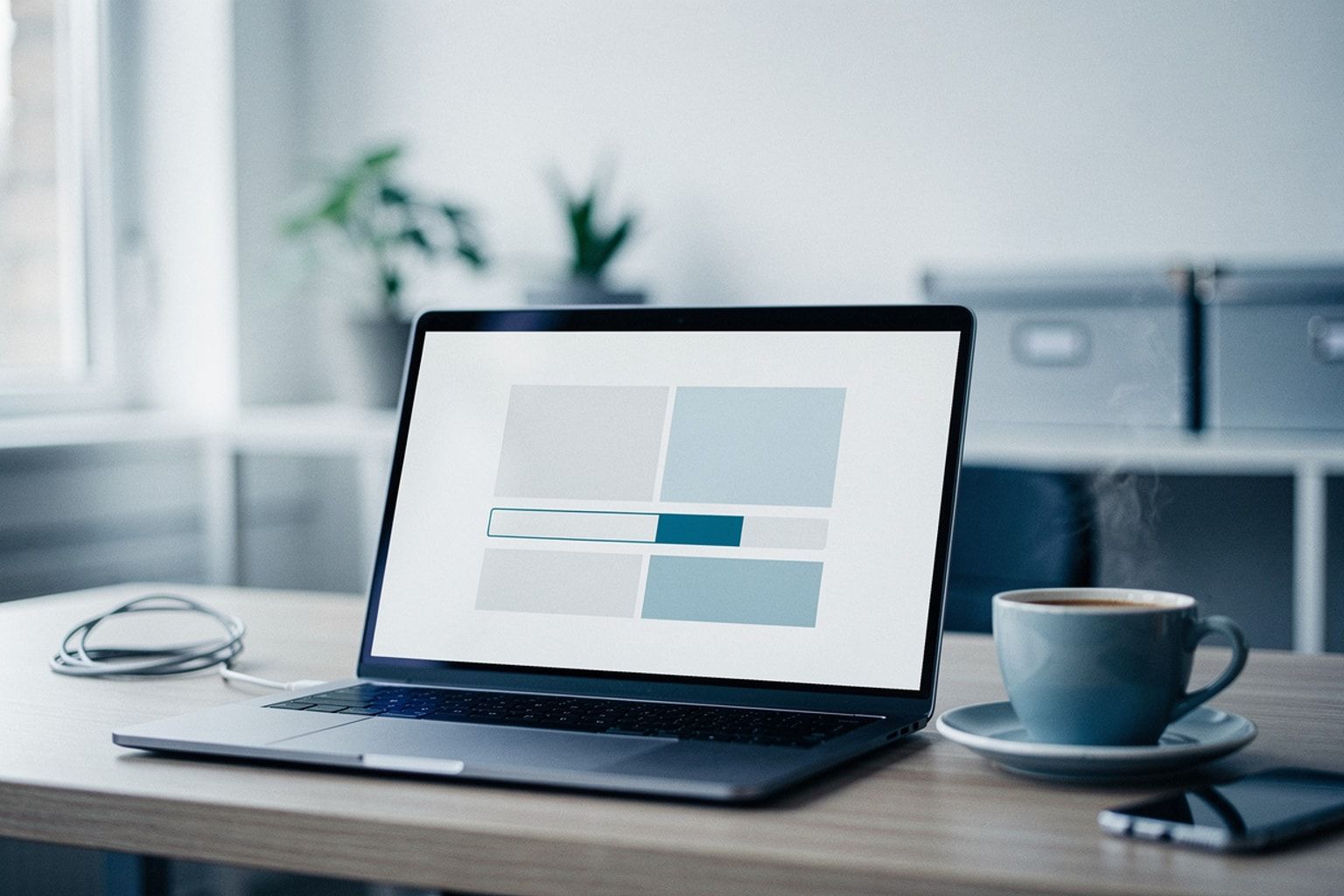 Laptop mit halb geladener Seite und Ladebalken, daneben ein Kaffee